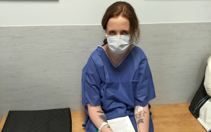 Młoda kobieta w niebieskim fartuchu medycznym czeka w poczekalni.