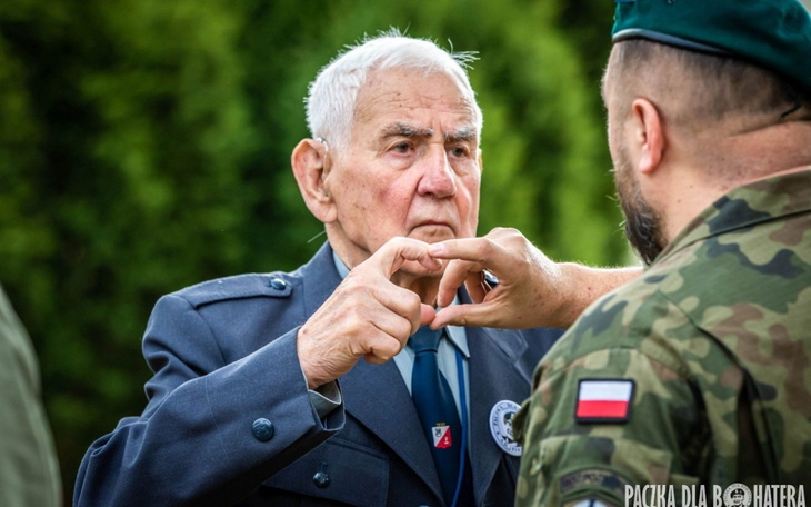 Starszy mężczyzna w mundurze, rozmawiający z żołnierzem.