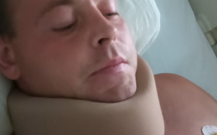 Mężczyzna z kołnierzem ortopedycznym, leży na łóżku.