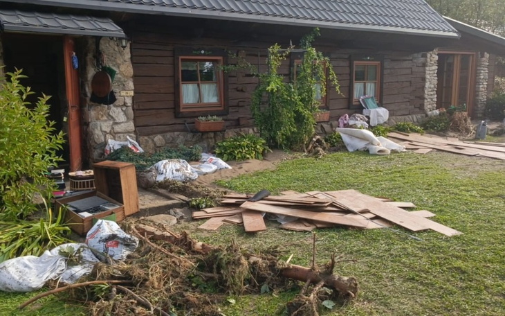 Zniszczony ogród przed drewnianym domem po powodzi.