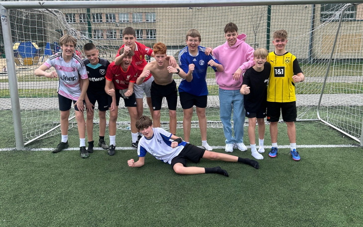 Grupa chłopców pozująca do zdjęcia na boisku piłkarskim.