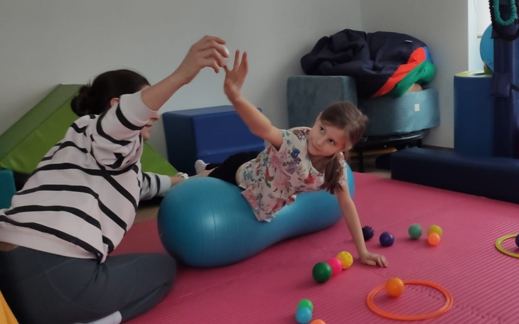 Dziecko bawi się w terapii, korzystając z kolorowych zabawek.