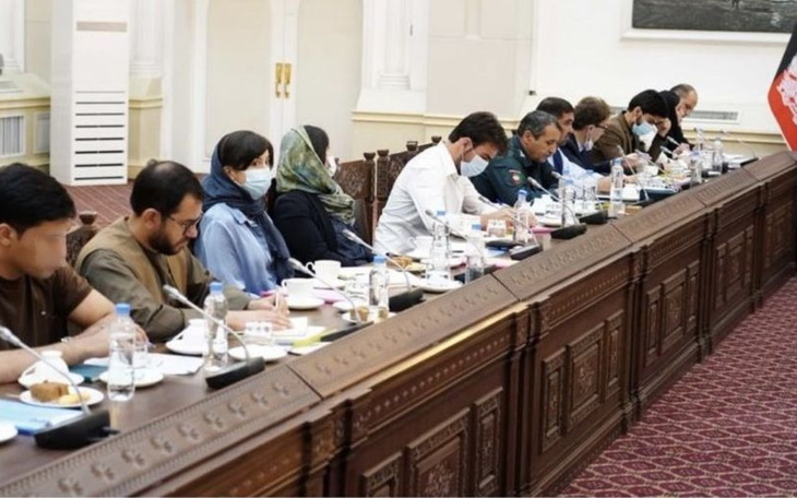 Grupa ludzi siedzących przy stole, prowadzących dyskusję.