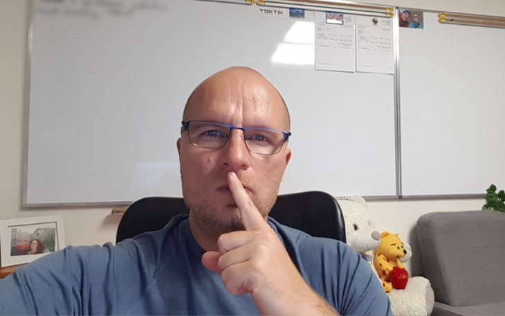 Mężczyzna z palcem na ustach, proszący o ciszę.