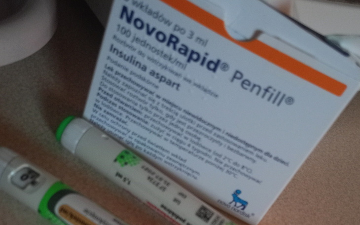 Opakowanie insuliny NovoRapid oraz strzykawki na stole.