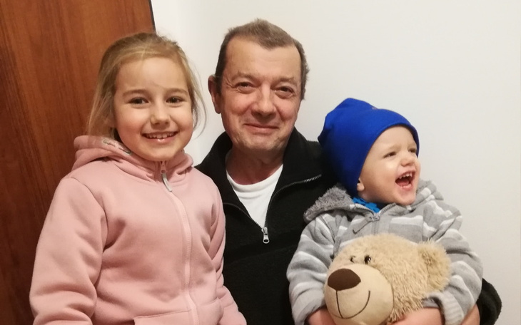 Dzieci z dziadkiem, uśmiechnięte i szczęśliwe.