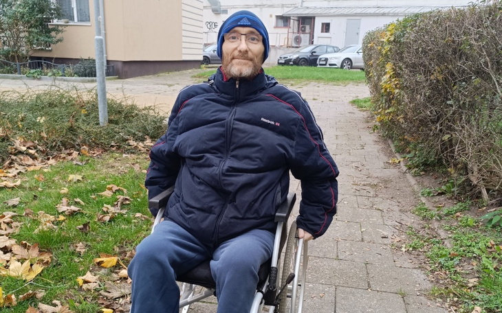 Mężczyzna na wózku inwalidzkim na chodniku w parku.