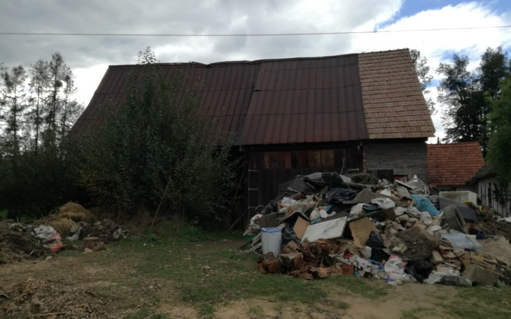 Zniszczony budynek z dużą stertą śmieci w otoczeniu.