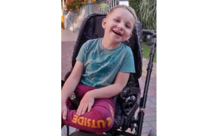 Uśmiechnięty chłopiec w wózku inwalidzkim.