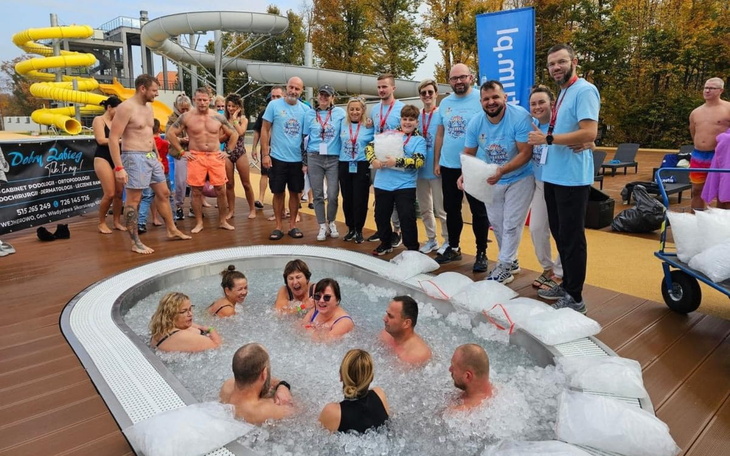 Grupa ludzi w strojach kąpielowych przy basenie.