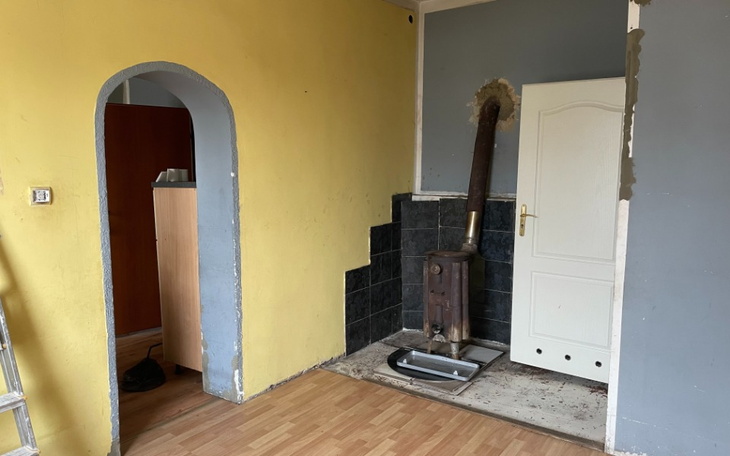 Pusty pokój z żółtymi ścianami i piecem, gotowy do remontu.