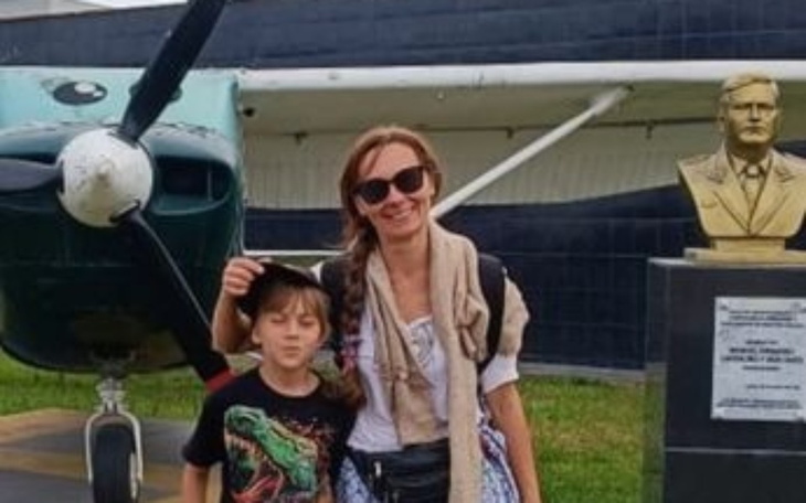 Kobieta z dzieckiem przy samolocie i popiersiu.