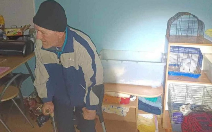 Starszy mężczyzna siedzący na krześle, z laską w ręku.