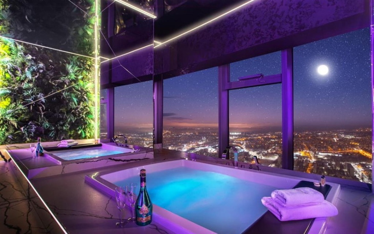 Nowoczesna łazienka z widokiem na miasto nocą.