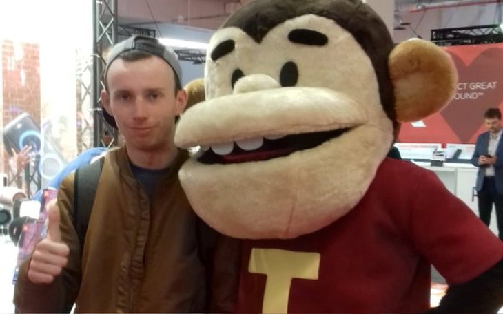 Osoba z maskotką małpy, pozująca z uśmiechem.