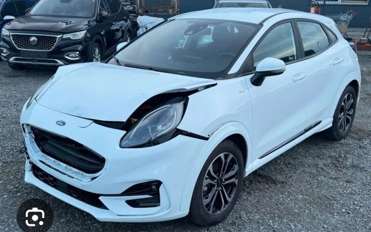 Uszkodzony biały samochód na parkingu.