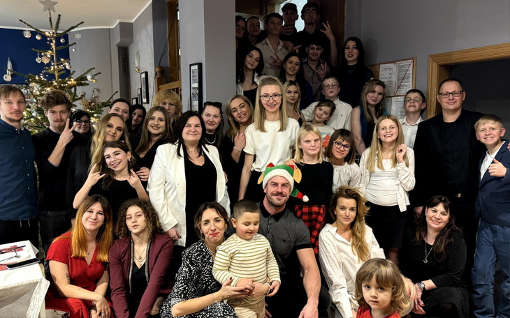 Grupa ludzi w eleganckich strojach, pozująca na przyjęciu świątecznym.