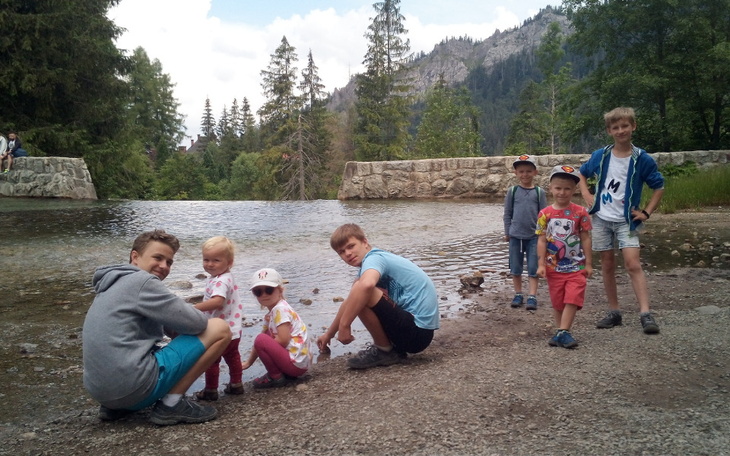 Dzieci bawiące się nad wodą w otoczeniu górskiej przyrody.