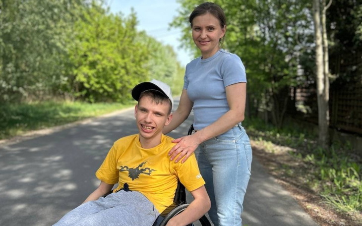 Kobieta z dzieckiem na wózku inwalidzkim na drodze w parku.