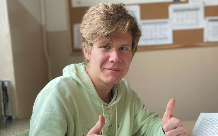 Młody mężczyzna z kciukami w górę, uśmiechający się do kamery.