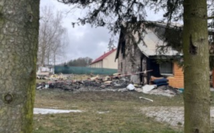 Zniszczony dom po pożarze, otoczenie z drzewami.