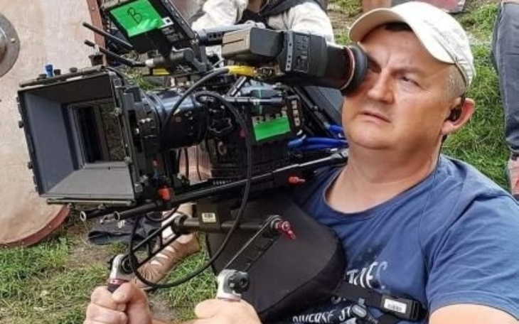 Mężczyzna z kamerą filmową, skupiony na pracy.