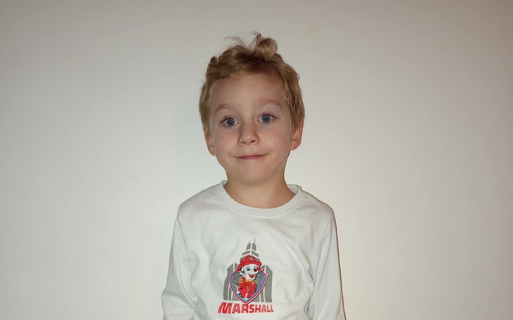 Chłopiec w białej koszulce z uśmiechem na twarzy.