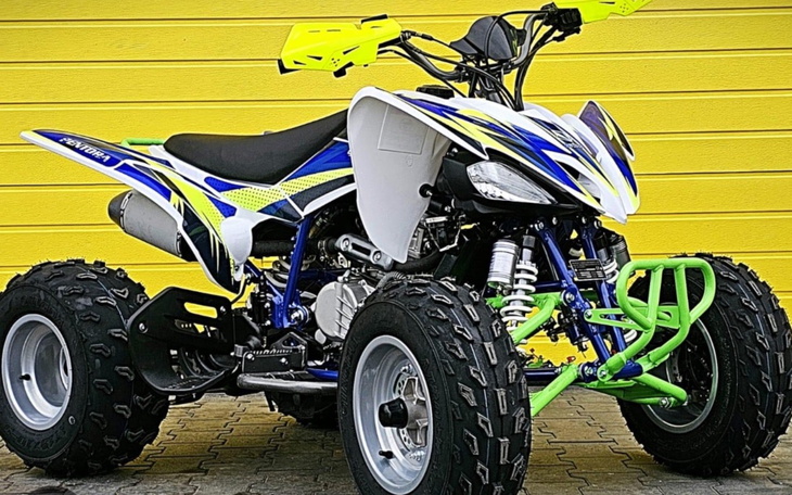 Nowoczesny quad w kolorze niebiesko-zielonym na tle żółtej ściany.