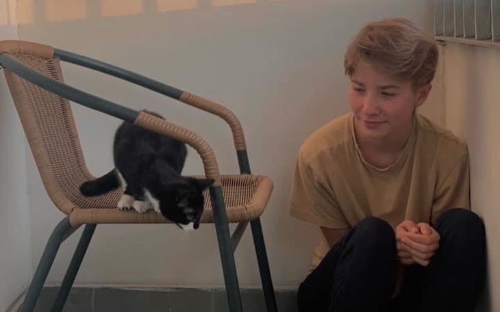 Chłopiec siedzi obok kota, który bada krzesło.
