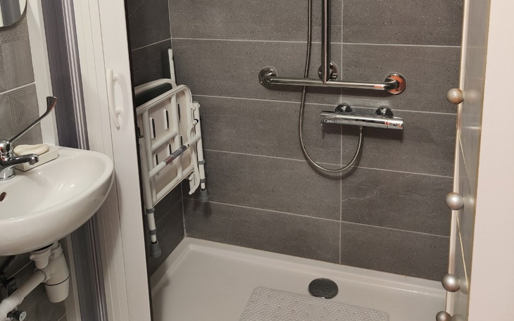 Nowoczesna łazienka z prysznicem i uchwytami dla osób z niepełnosprawnościami.