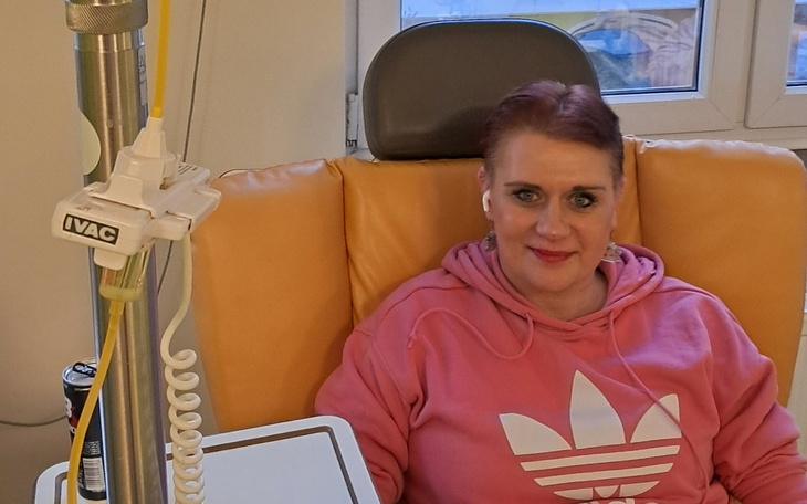 Kobieta w różowej bluzie, siedząca na fotelu w szpitalu.