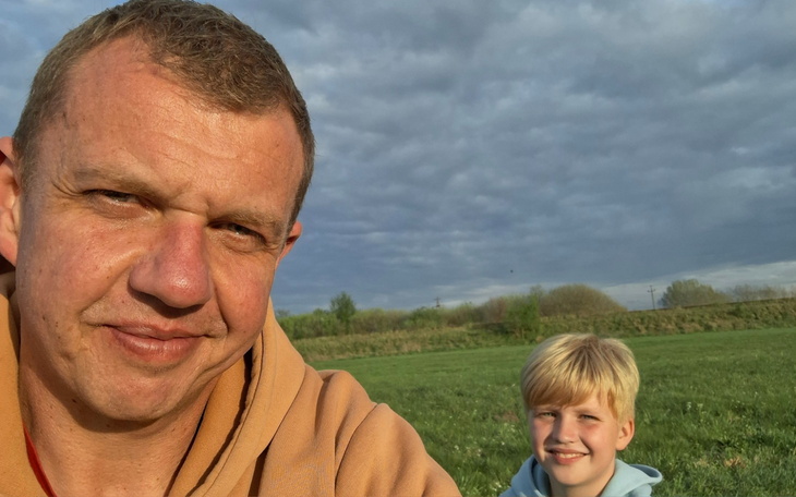 Mężczyzna z dzieckiem na tle zielonego krajobrazu.