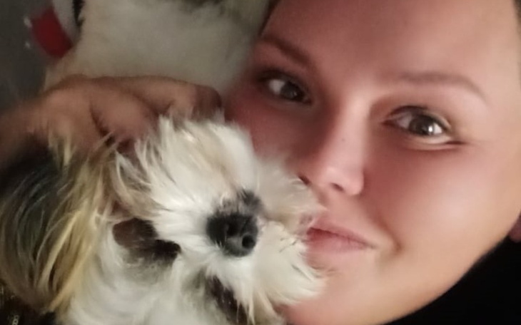 Kobieta przytulająca małego psa, obie uśmiechają się.