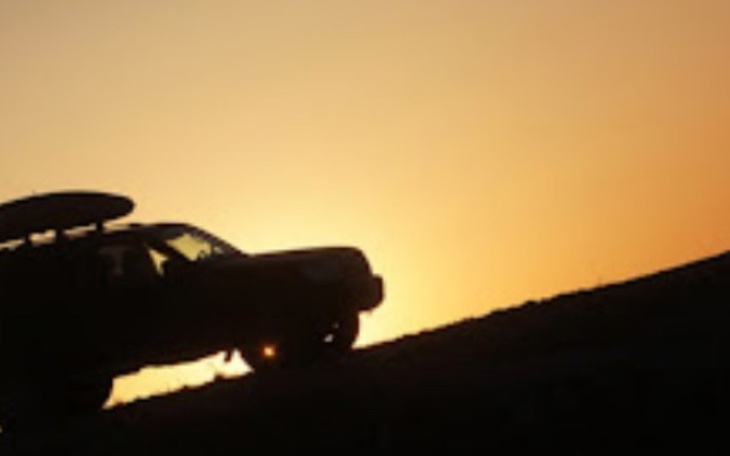 Samochód terenowy na tle zachodzącego słońca.