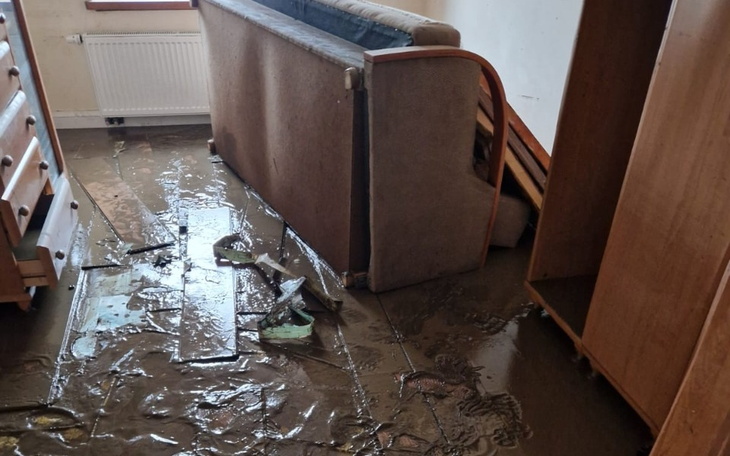 Zniszczone wnętrze pomieszczenia, woda na podłodze.