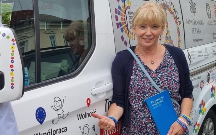 Kobieta przy samochodzie z logo, promująca wolontariat.