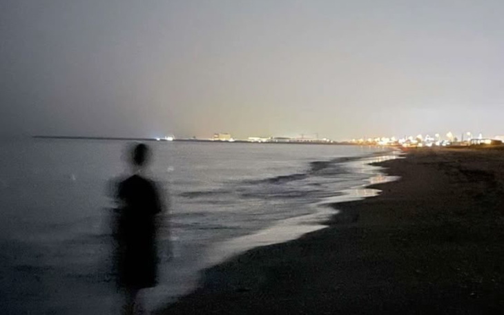 Człowiek stojący na plaży w nocy.