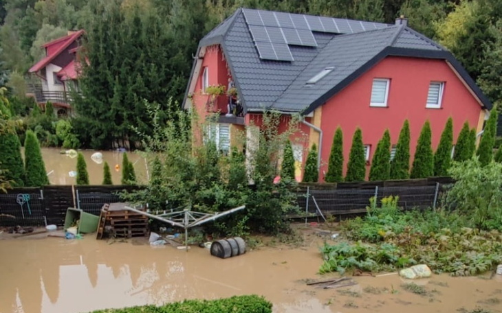 Zalany teren wokół domu, z widocznymi skutkami powodzi.
