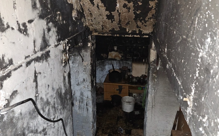 Zniszczona klatka schodowa po pożarze, z czarnymi ścianami i zniszczonymi przedmiotami.