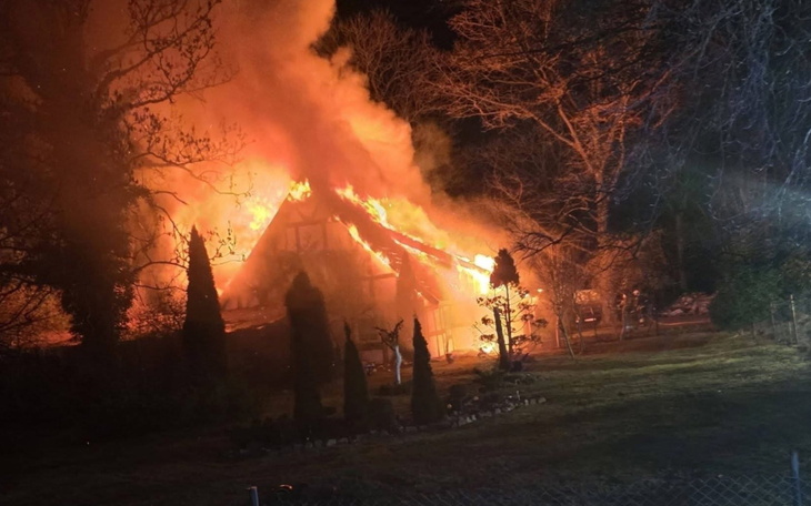 Pożar strawił dach budynku, widać płomienie i dym.
