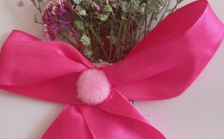 Różowa wstążka z suszonymi kwiatami, elegancka dekoracja.