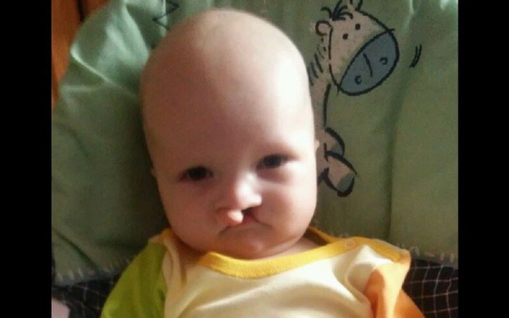 Małe dziecko z poważnym wyrazem twarzy, siedzące na foteliku.