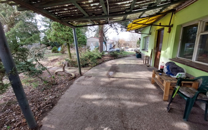 Widok na zewnętrzny taras domu z zielonym otoczeniem.