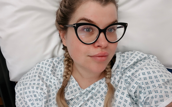 Kobieta w szpitalnym łóżku, w szpitalnej koszuli.