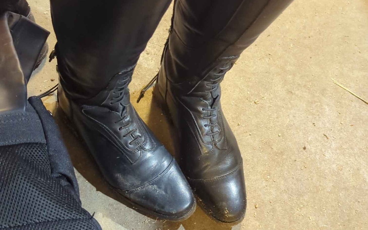 Czarne buty na tle podłogi, widać detale.