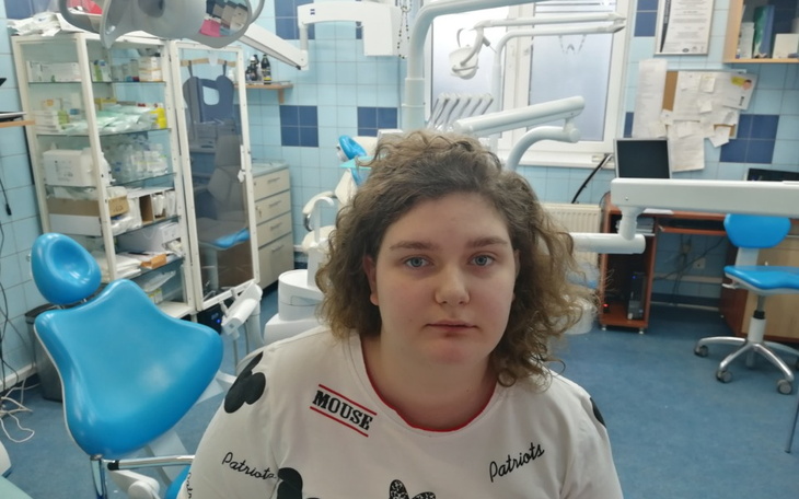 Młoda kobieta w gabinecie dentystycznym, z poważnym wyrazem twarzy.