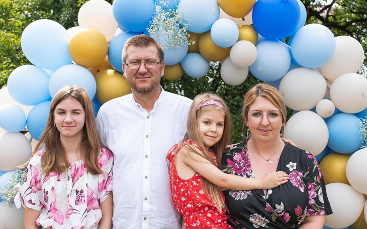 Rodzina pozująca przed kolorowym tłem na przyjęciu.