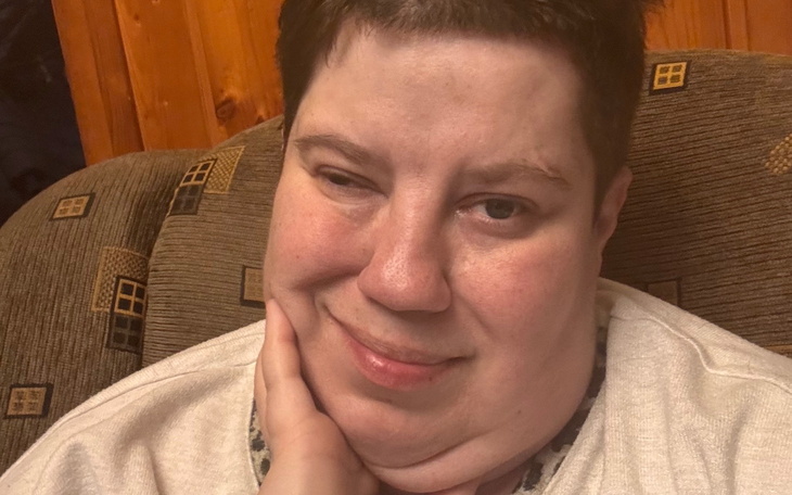 Portret kobiety z uśmiechem, siedzącej na kanapie.