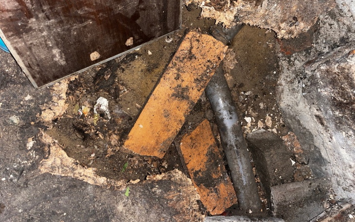 Wykop z drewnianymi deskami i rurą w ziemi.