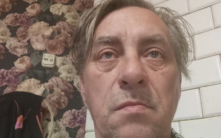 Mężczyzna z zamyślonym wyrazem twarzy w pomieszczeniu.
